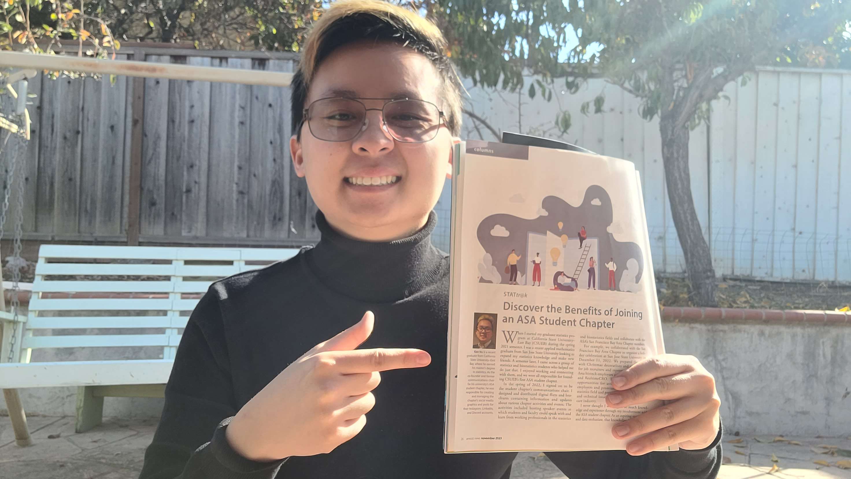 Me in a black turtleneck outside in my sunny backyard holding a folded copy of the Significance magazine with the page flipped to my article 'Discover the Benefits of Joining an ASA Student Chapter' in it.