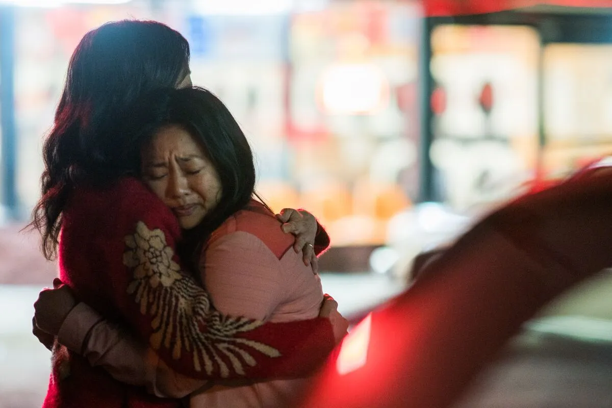 A picture of a young Asian woman hugging her mother at night in front of a laundromat in a parking lot as seen in the movie 'Everything Everywhere All at Once'.