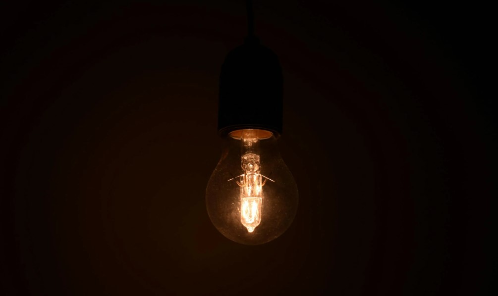A picture of a light bulb from a roof in the midst of darkness.