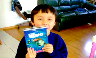 A picture of six year old Ken Vu holding up his DVD copy of the movie Finding Nemo.
